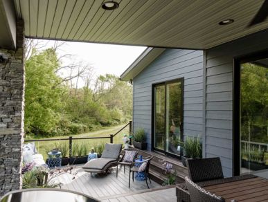backyard deck exterior home remodeling partially under an overhang with blue siding, white decking, and patio furniture
