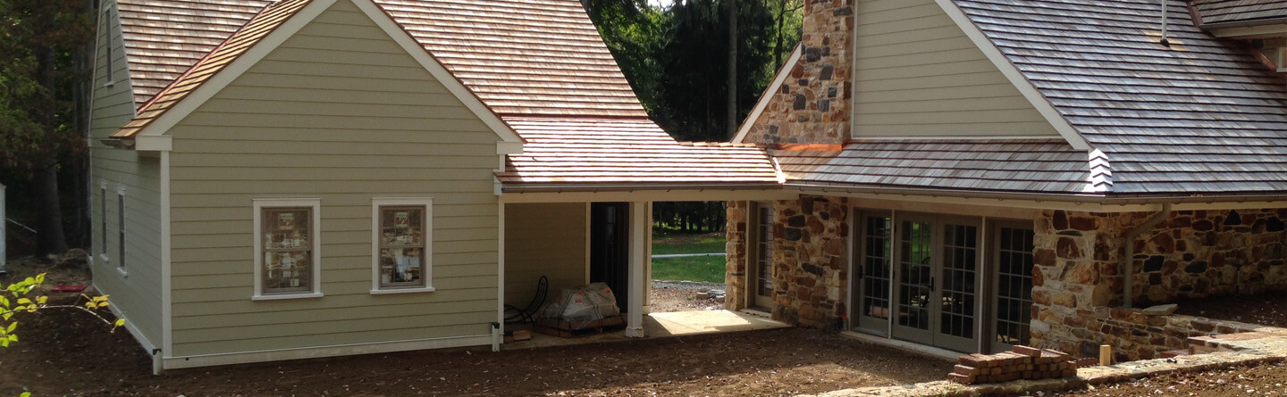 large house with cedar shake roof and walk way to attached part of the home