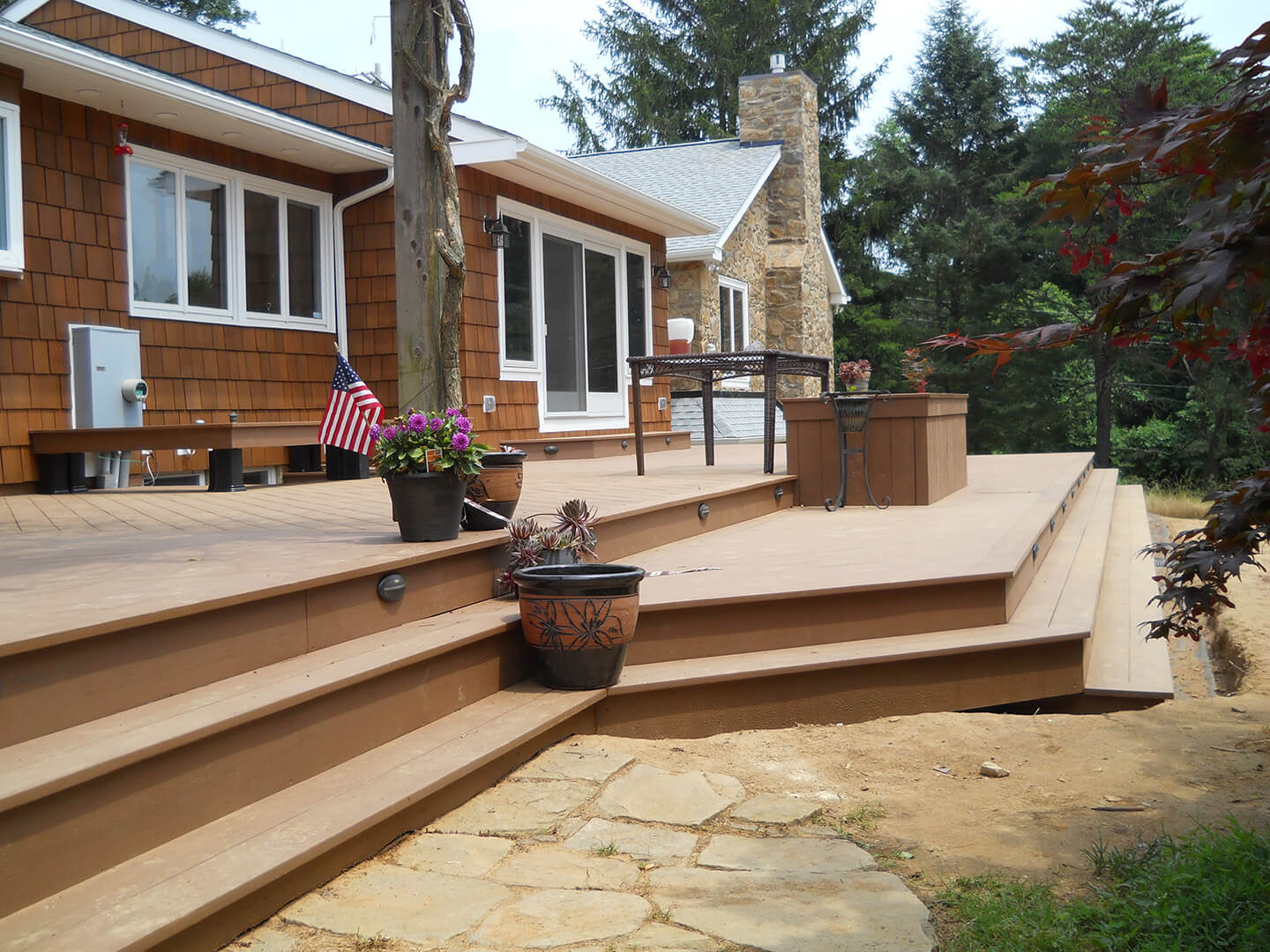 side view of tan azek deck with planters, lights, and a fire pit
