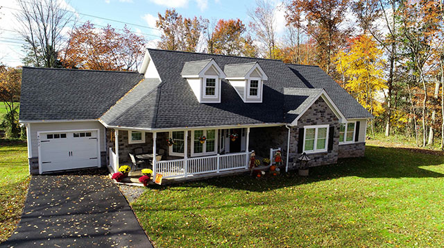 large cape cod stucco home with covered porch and one car attached garage