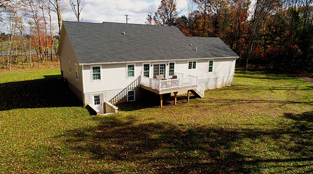 back view of large house with custom deck patio and staircase