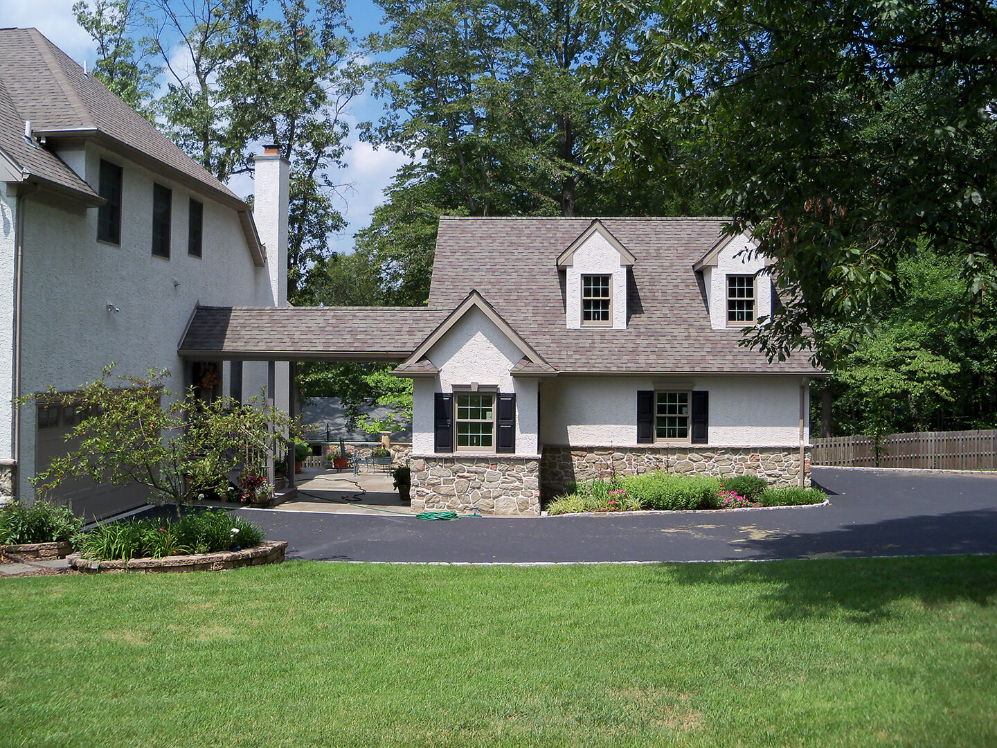 attached stucco and stone custom garage with walkway to house in cape cod style