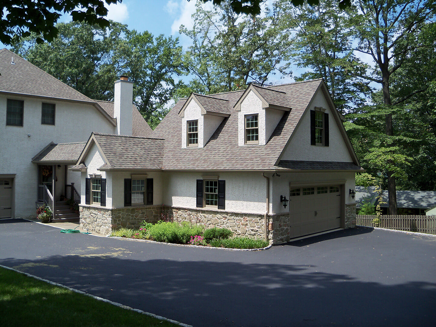 cape cod style stucco and stone garage addition with second floor