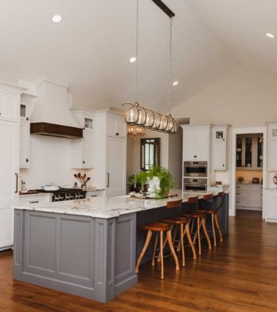 custom interior kitchen remodel complete with white cabinets, large gray island with granite, and new appliances