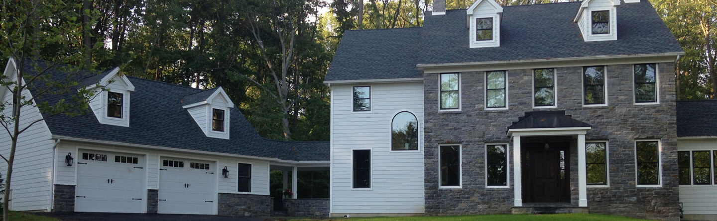 large stone custom home with attached cape cod garage